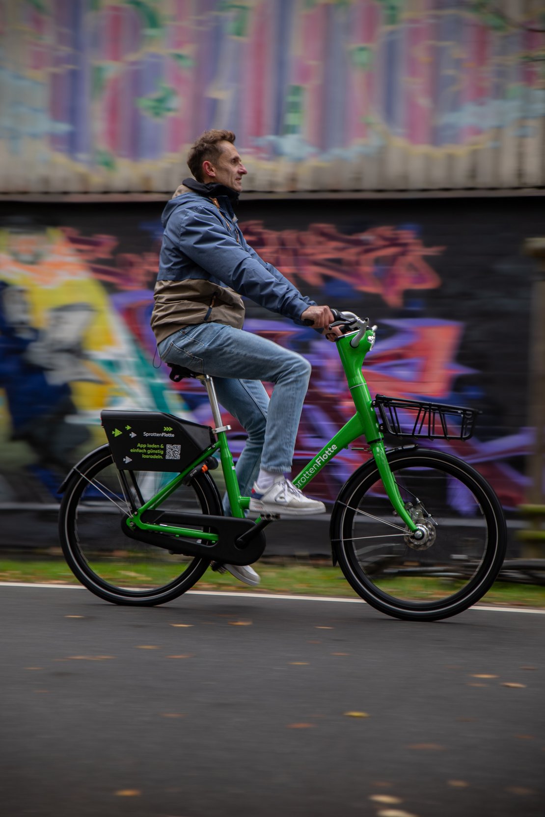 Ein Mann fährt auf einem grünen Fahrrad des Bikesahring-Systems Sprottenflotte.