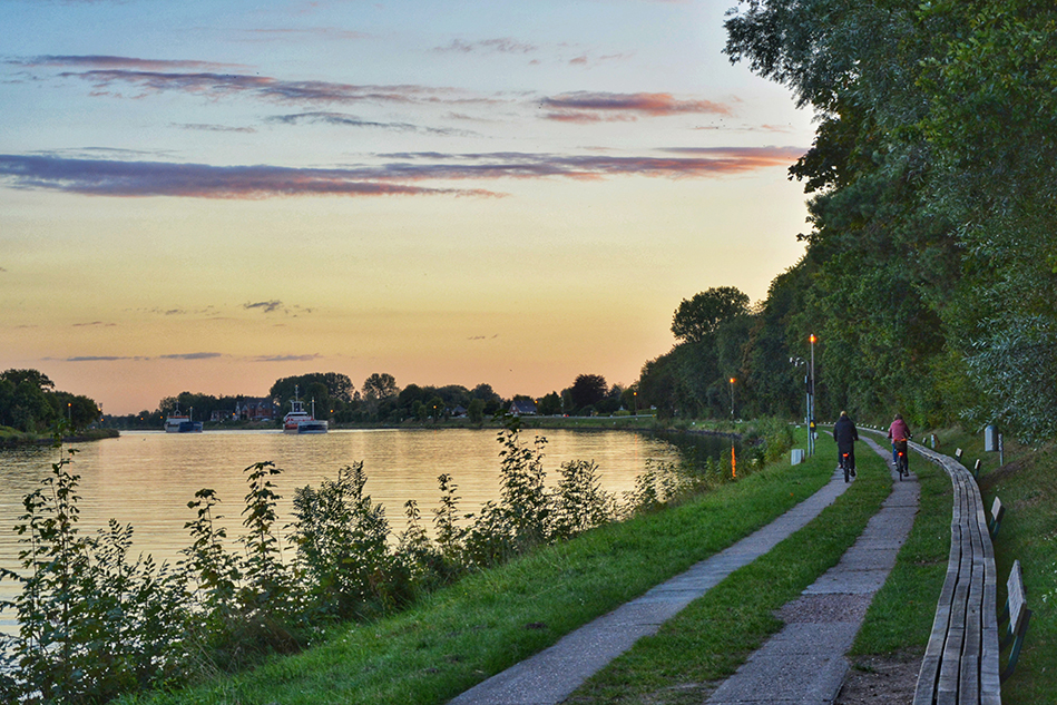 Der Nord-Ostsee-Kanal in der Abenddämmerung mit Radfahrern und der Längsten Bank
